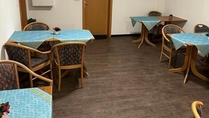 Un espace repas avec plusieurs tables et chaises, une porte portant le numéro 15 et un meuble fixé au mur.