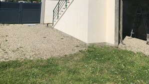 Ein modernes, zweistöckiges Haus mit überdachter Garage, einer grünen Treppe und einem Schotterweg.