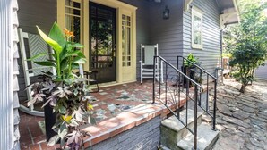 Uma casa com varanda coberta, um caminho de tijolos e uma escadaria que leva à entrada.