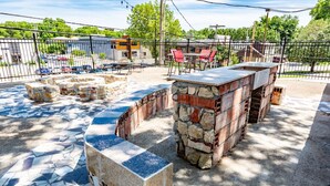 Une terrasse extérieure avec des sièges en pierre, un espace barbecue et un sol carrelé.