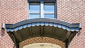 Un bâtiment en briques avec un escalier en pierre menant à une entrée sombre.
