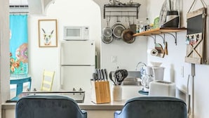 Cucina con due sgabelli da bar, un forno a microonde, un lavandino e diversi utensili da cucina.