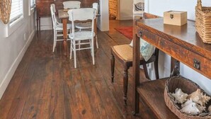 A spacious dining area with a wooden table and chairs, a ceiling fan, and a view of the kitchen. - The Danish Nydam - A Sailor’s Mooring (Christiansted)