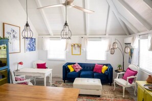 A cozy attic room with a blue sofa, white furniture, and a ceiling fan. - The Royal Wait - An Elegant Retreat (Christiansted)