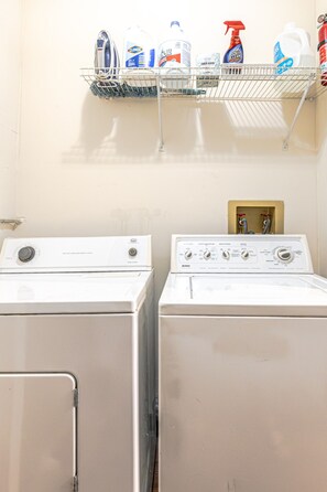 A laundry area with two front-loading washers and a shelf above containing cleaning supplies. - Trailside Retreat in the City (Tulsa)