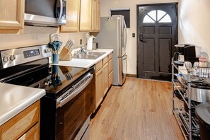 A kitchen with wooden cabinets, a stainless steel refrigerator, a dishwasher, and a stove. - Trailside Retreat in the City (Tulsa)