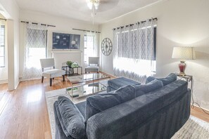 A living room with a sofa, chairs, a coffee table, and a lamp. - Trailside Retreat in the City (Tulsa)