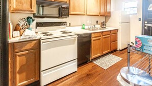 A kitchen with wooden cabinets, a stove, a microwave, a dishwasher, and a refrigerator. - Trailside Retreat in the City (Tulsa)