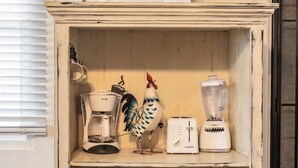 A kitchen cabinet with a microwave, toaster, blender, and decorative rooster. - The Rooster’s Perch - A Quaint Island Homestead (Christiansted)