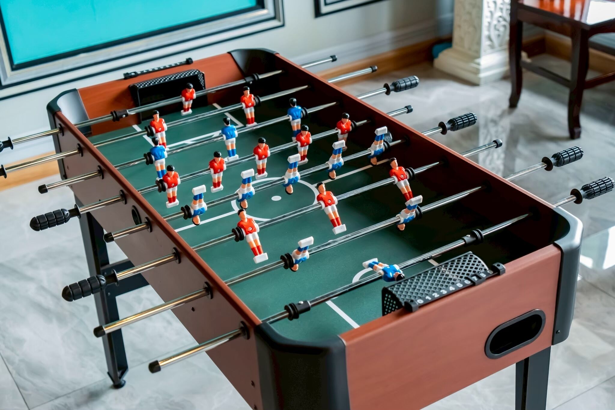 A foosball table with players in red and blue uniforms.