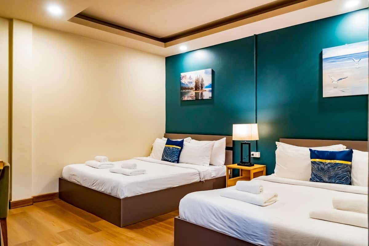 Habitación de hotel con dos camas individuales, una mesita de noche con lámpara y un cuadro en la pared.