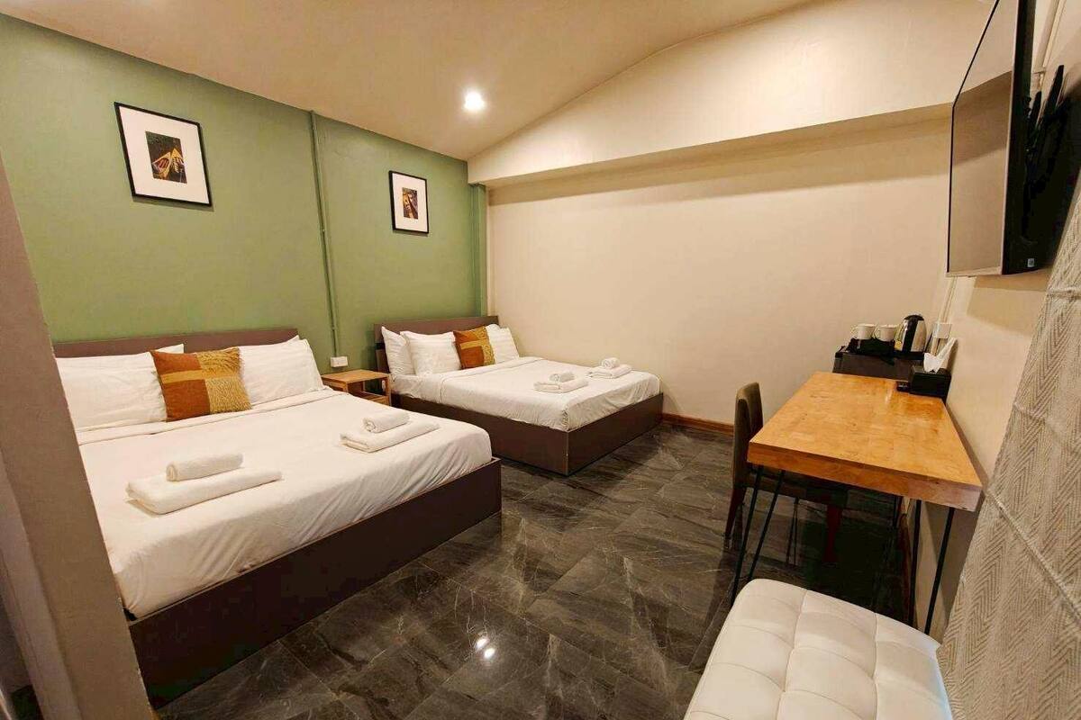 Una habitación de hotel con dos camas, un escritorio de madera y un televisor montado en la pared.