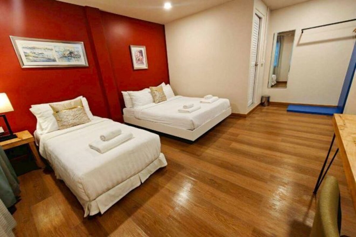 Habitación de hotel con dos camas, suelo de madera y paredes rojas.