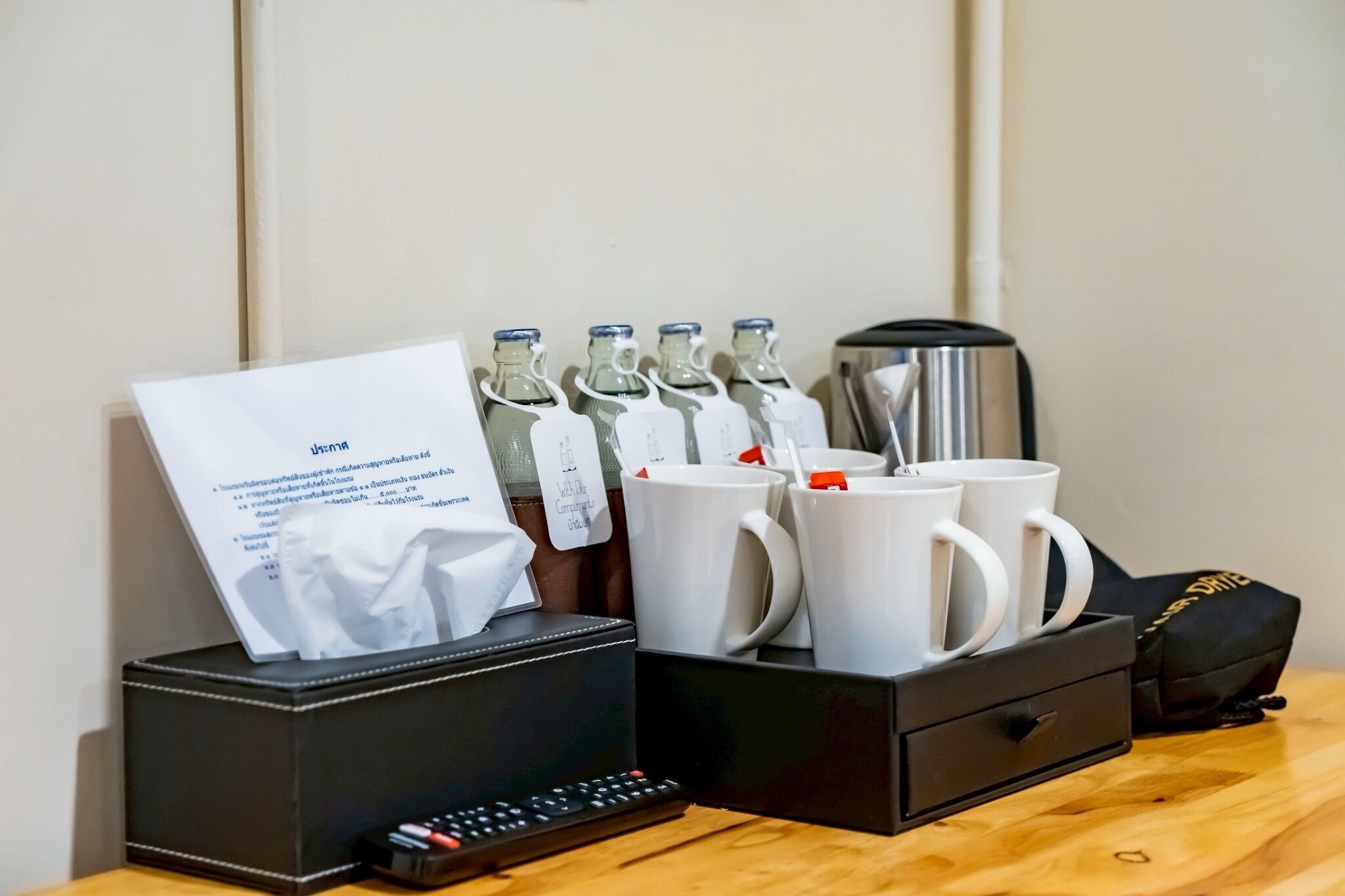 Una habitación de hotel con minibar, cafetera y un juego de tazas blancas.