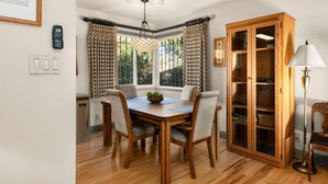 A dining area with a wooden table, four chairs, a chandelier, patterned curtains, a wooden cabinet, and a floor lamp. - Private retreat in the heart of Chico, just moments away from the enchanting Lower Bidwell Park (Chico)