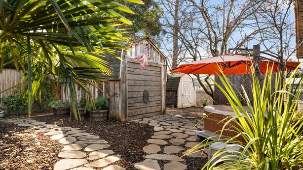 A stone pathway leading to a wooden shed, surrounded by lush greenery and a red umbrella. - Private retreat in the heart of Chico, just moments away from the enchanting Lower Bidwell Park (Chico)