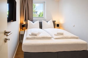 A hotel room with a bed, two bedside tables, a window with curtains, and a view of the outside. - Vacation rental (new construction 2023) in prime location with fireplace and bal (Winterberg)