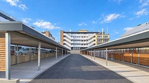 A covered parking area with multiple levels of parking and a building in the background. - Vacation rental (new construction 2023) in prime location with fireplace and bal (Winterberg)