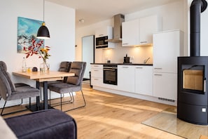 A modern kitchen with white cabinets, a black stove, and a dining area with a table and chairs.