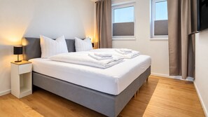 A modern hotel room with a bed, a nightstand, a lamp, and a window with curtains. - Vacation rental (new construction 2023) in prime location with fireplace and bal (Winterberg)