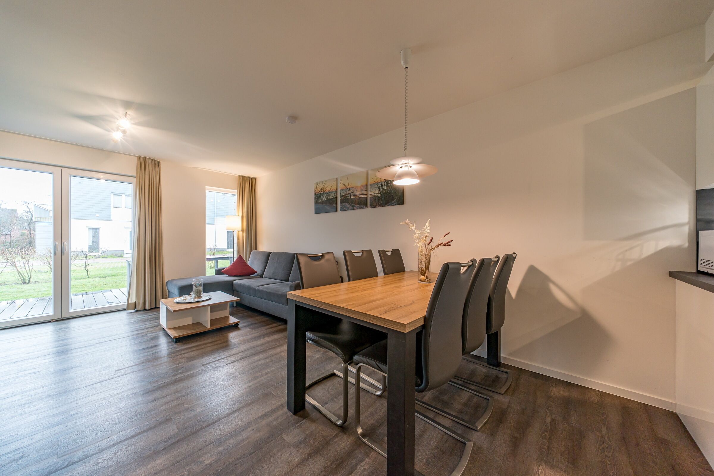 Un salon moderne avec une table à manger, un canapé et de grandes fenêtres.