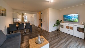 Un salon moderne comprenant un canapé, une table basse, un téléviseur et un coin repas.