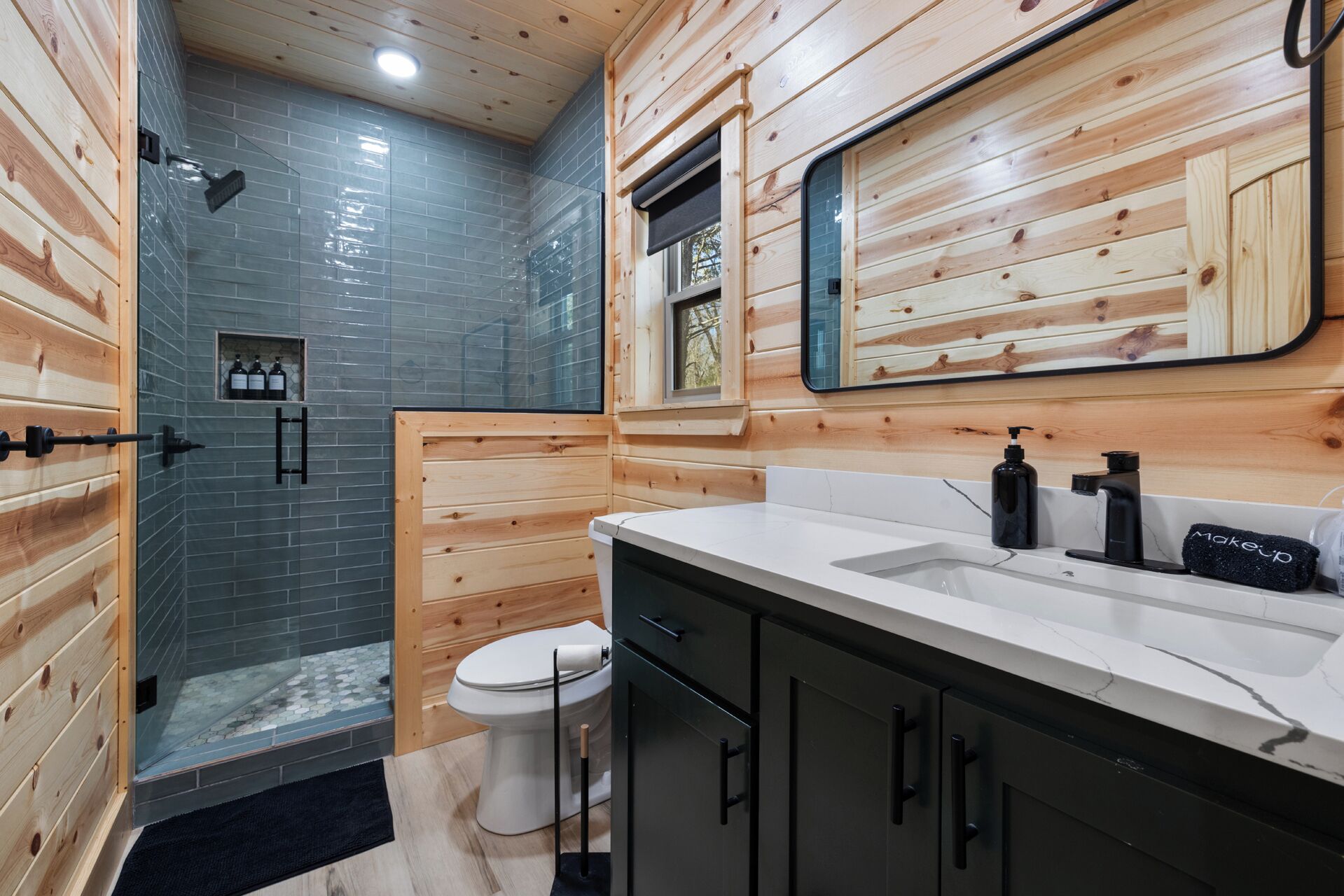 Une salle de bain moderne avec un intérieur en bois, une cabine de douche en verre, des toilettes blanches et un meuble-lavabo avec un miroir.