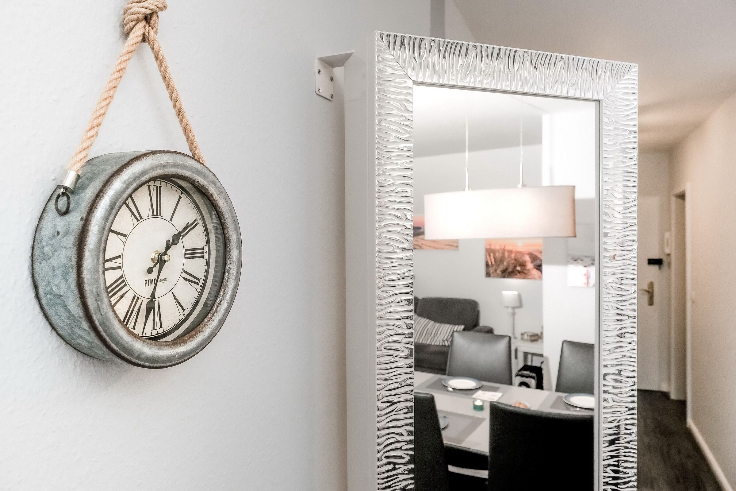 Een kamer met een landelijke wandklok en een grote spiegel met een structuurrijke lijst.