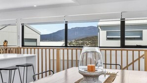 Une chambre moderne dotée d’une grande fenêtre, d’une table sur laquelle se trouve un chandelier en verre, et offrant une vue sur les montagnes.