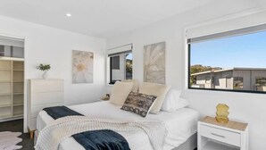 Une chambre moderne avec un grand lit, une table de chevet, une armoire et une fenêtre donnant sur un beau paysage.