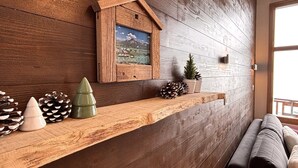 Un mur en bois avec une étagère où sont exposés des pommes de pin et un tableau encadré.