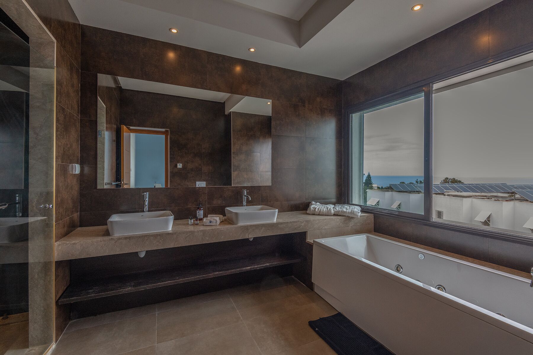 A modern bathroom with two sinks, a large bathtub, and a large mirror.