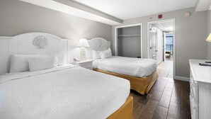 A hotel room with two beds, a nightstand, a lamp, and a view of the balcony. - Oceanfront Suite: Complimentary Breakfast 10th Flr (Myrtle Beach)