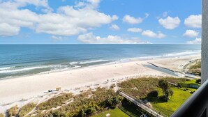 A beach view from a balcony with a clear sky and a sandy beach. - Oceanfront Suite: Complimentary Breakfast 10th Flr (Myrtle Beach)