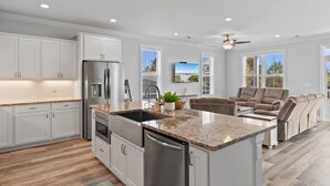 A modern kitchen with white cabinetry, a granite countertop, and stainless steel appliances.