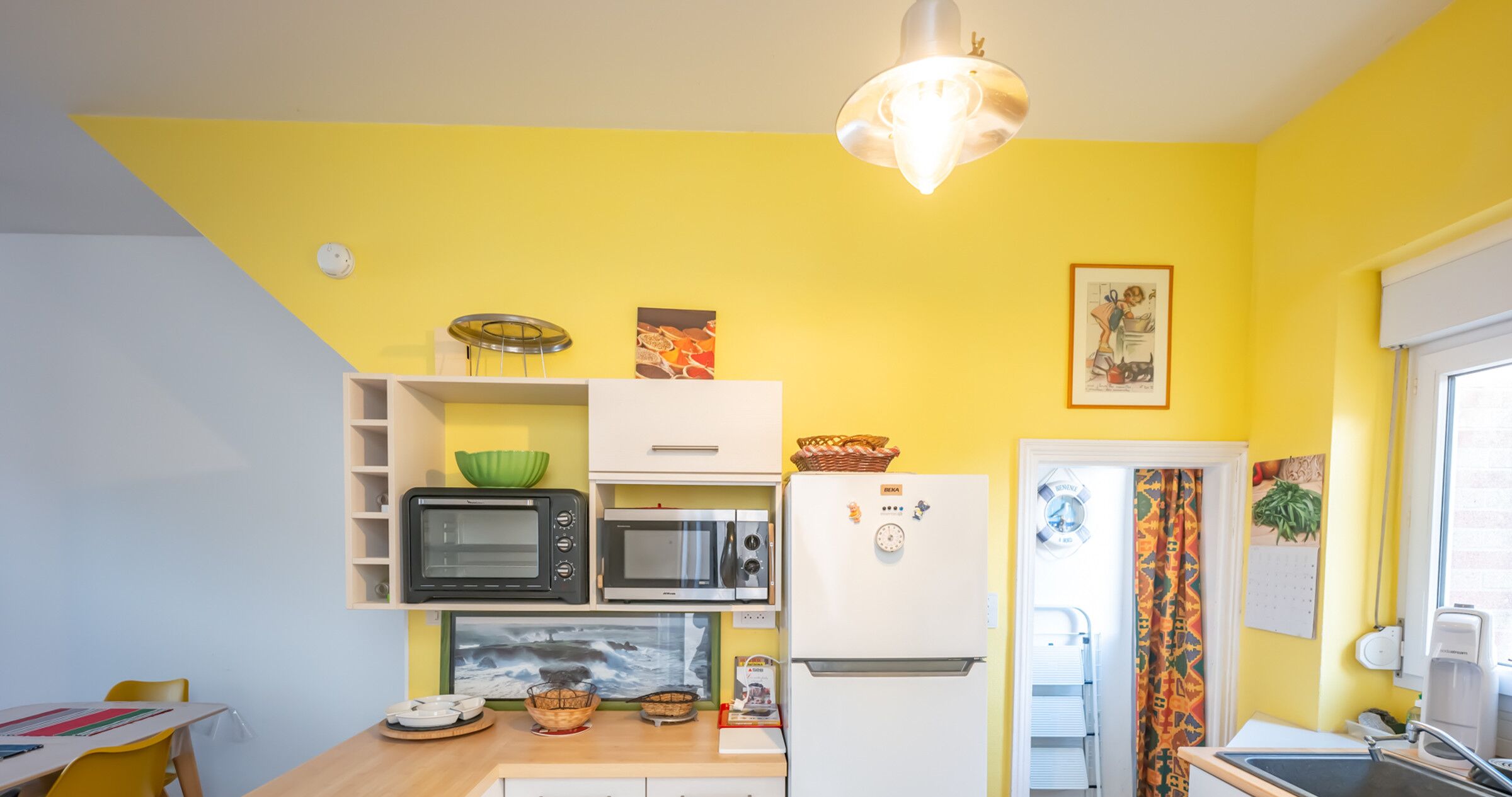 Una cucina compatta con microonde, forno e frigorifero. C'è un lavandino e un'area pranzo con tavolo e sedie.