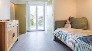 Ein Schlafzimmer mit einem Bett, einem Schminktisch und einer Tür, die auf einen Balkon führt.