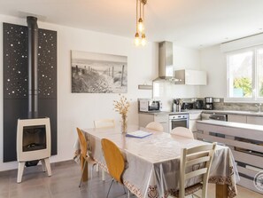 A modern kitchen with a central island, a built-in stove, and a microwave. There is a dining table with chairs and a vase of dried flowers. - Ideal House in Barneville-Carteret, near beach, pets allowed, secure parking (Barneville-Carteret)