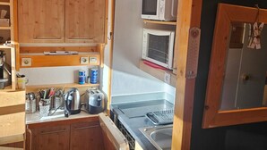A compact kitchen with wooden cabinets, a microwave, a toaster, and a sink.