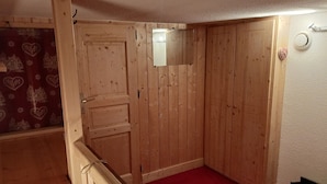 A wooden-paneled room with a red carpet, a door, and a small mirror on the wall.