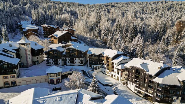 A snow-covered resort with multiple buildings, including a tower, and a forested mountain backdrop. - Cozy 2-room flat without lift, for 4/5 people, Morillon 1100 (Morillon 1100)