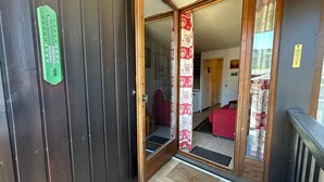 A wooden door with a green thermometer, a red curtain, and a red sofa inside. - Cozy 2-room flat without lift, for 4/5 people, Morillon 1100 (Morillon 1100)