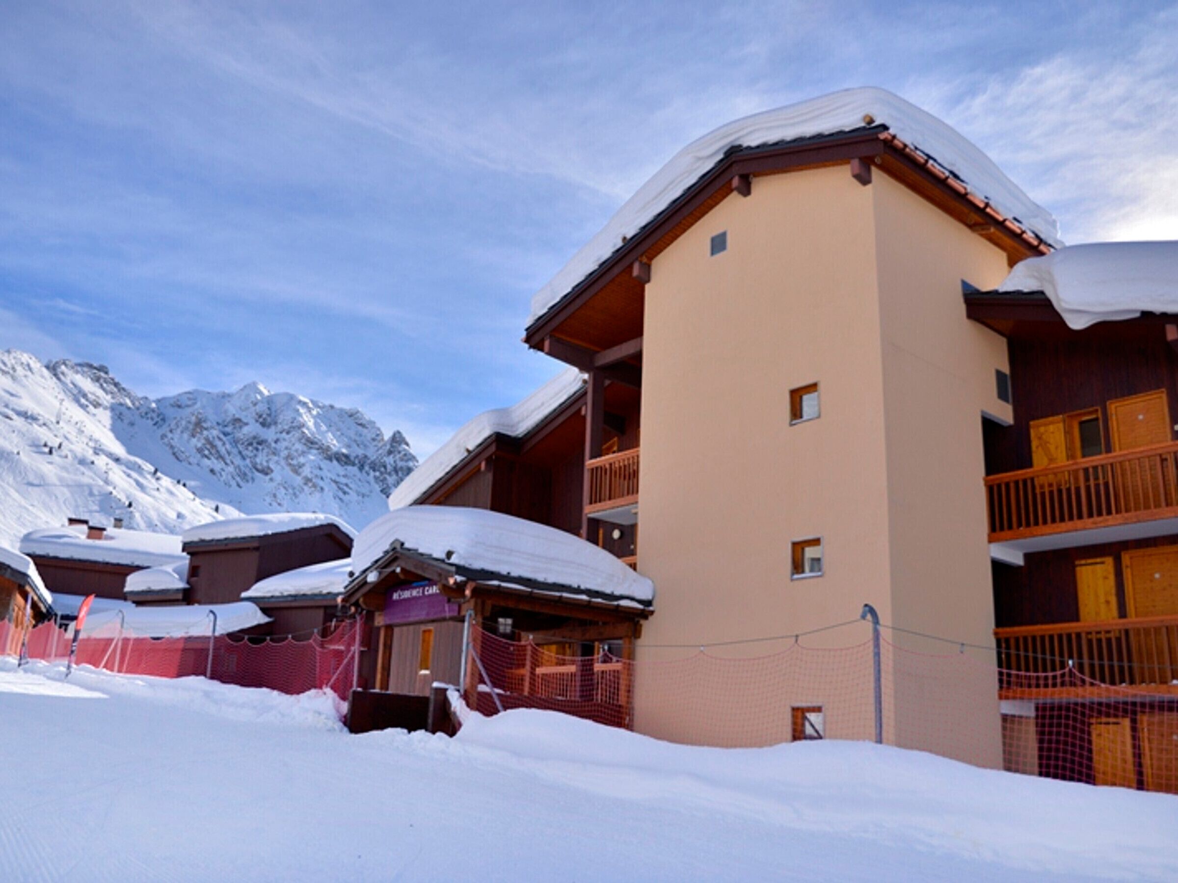 A snow-covered building with multiple balconies and a mountainous backdrop.