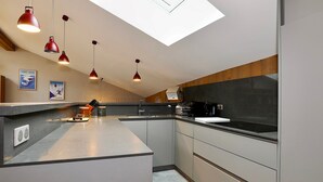 A modern kitchen with a skylight, pendant lights, and a large island.