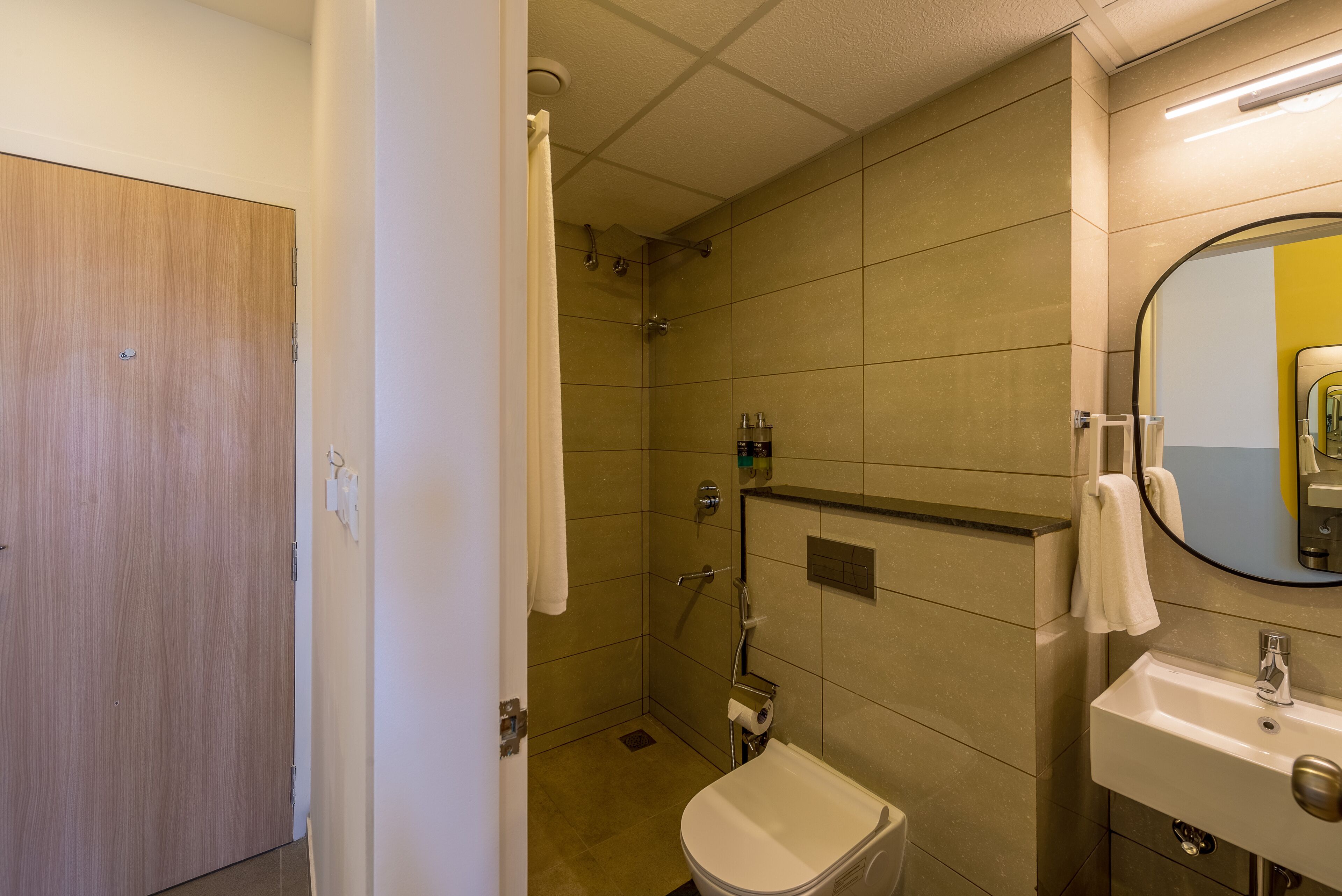 A bathroom with a shower, toilet, sink, and a mirror.