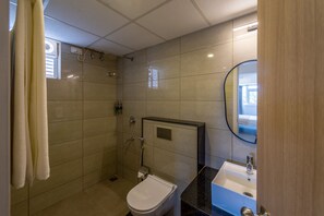 A bathroom with a shower, toilet, sink, and mirror. - Olive Hotel JP Nagar by Embassy Group (Bengaluru)