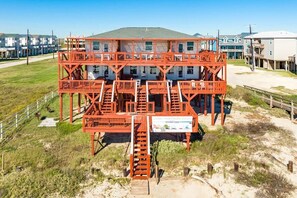 Eine mehrstufige Konstruktion mit einer Treppe zu einer erhöhten Plattform, umgeben von einer Sandfläche mit einem Schild, das ein Resort kennzeichnet.