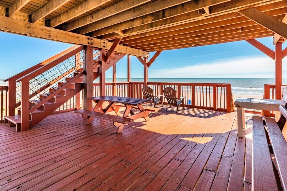 Une terrasse en bois avec des tables et des chaises pour pique-niquer, offrant une vue sur l’océan.