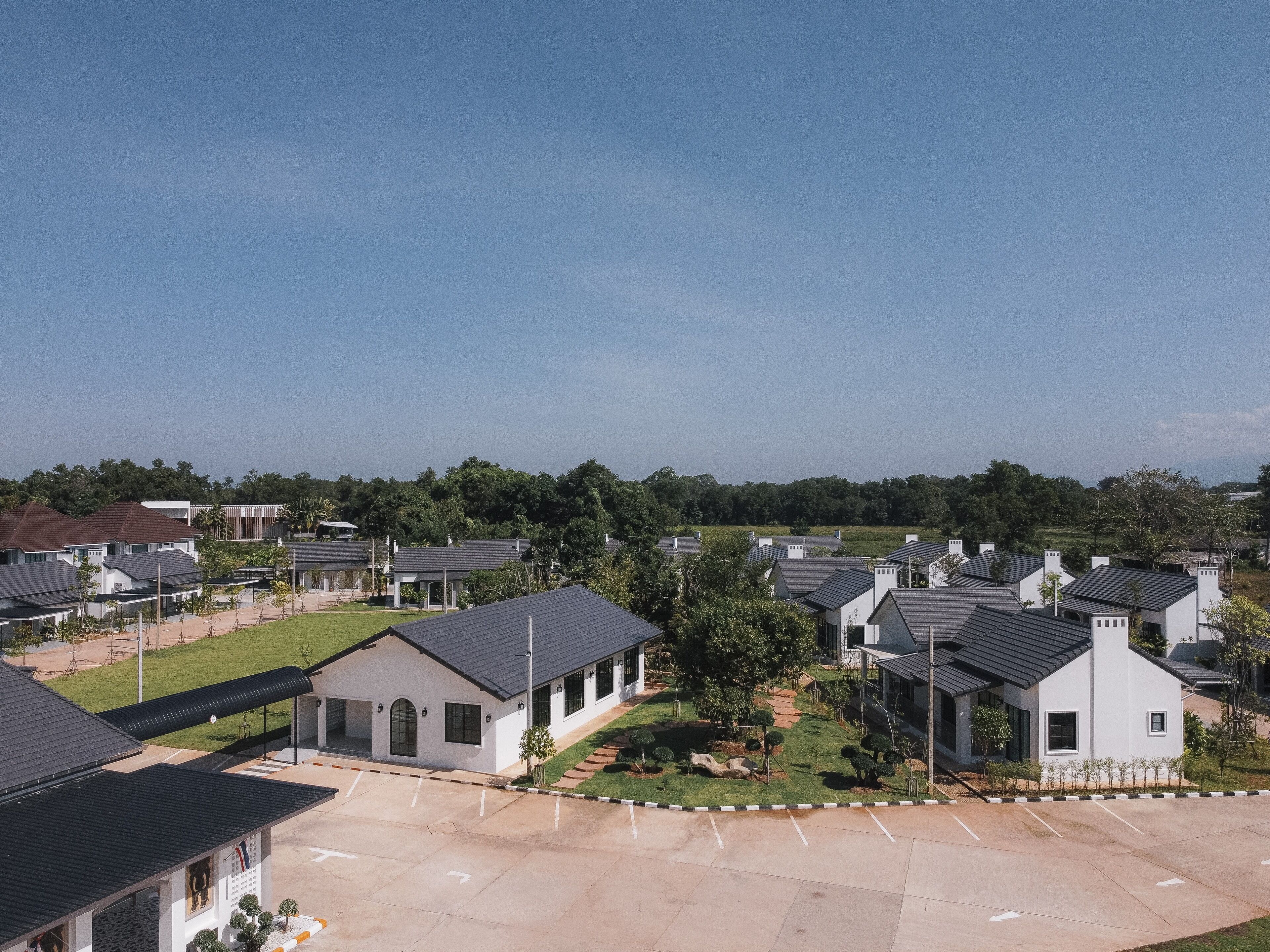 A residential area with modern houses, a parking lot, and a green lawn.