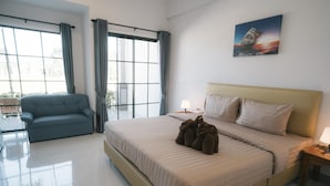 Una habitación de hotel moderna con una cama grande, un sofá, una ventana con cortinas y un cuadro en la pared.